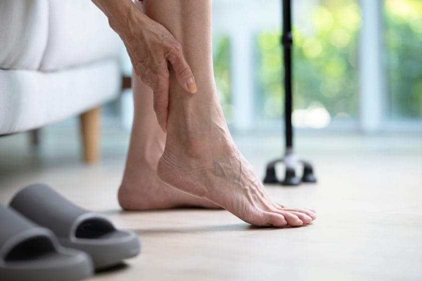 Senior woman holding ankle and suffering from foot arthritis pain.