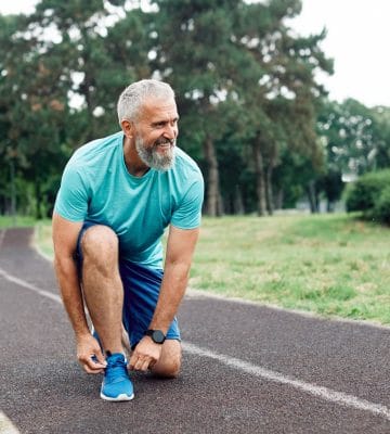 Man tying his running shoes on a track.