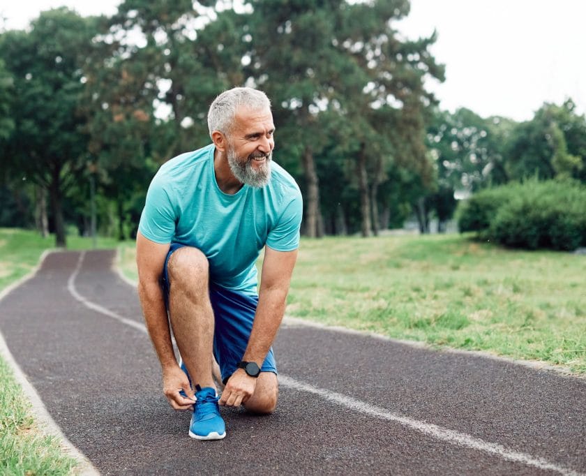 Man tying his running shoes on a track.