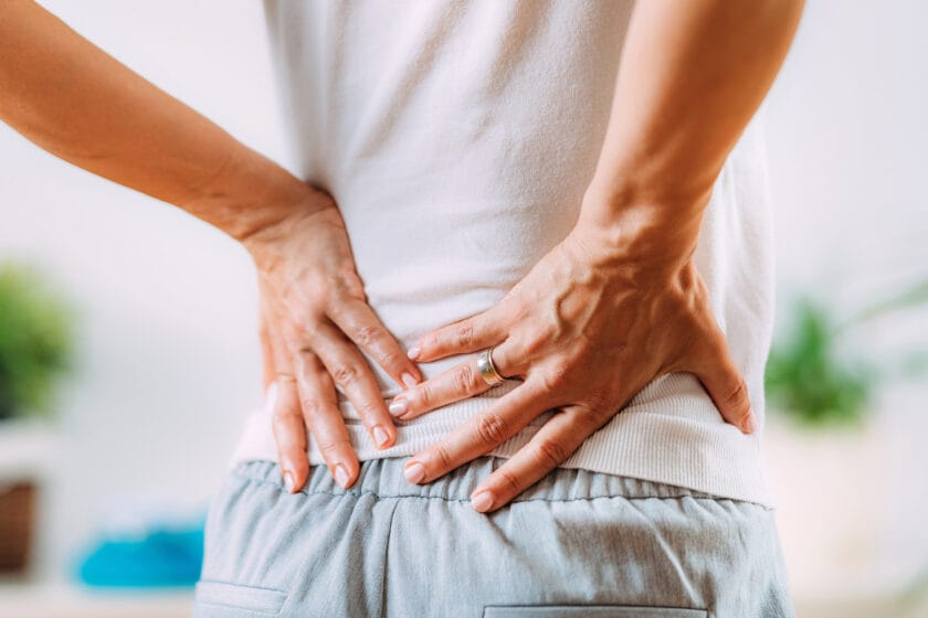 Person with lower back pain holding their lower back with both hands