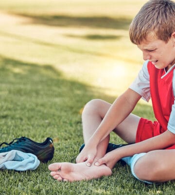 Boy holding foot in pain due to Sever's disease